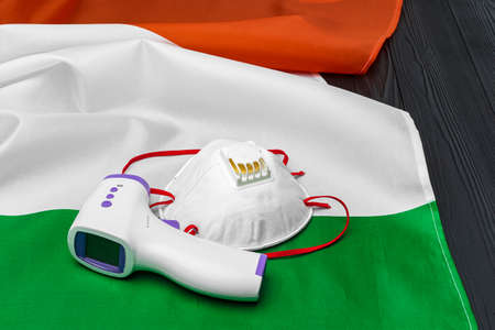 Medical face mask and contactless thermometer on flag of Italyの写真素材
