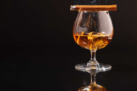 Burning cigar and glass of whisky on black backgroundの写真素材
