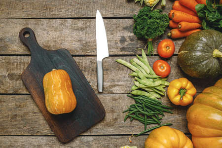 Wooden cutting board with autumn vegetables on wooden tableの写真素材