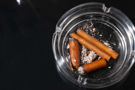 Ash tray full of cigarette butts on black backgroundの写真素材