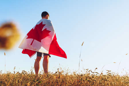 Man with a flag of Canada standing in field