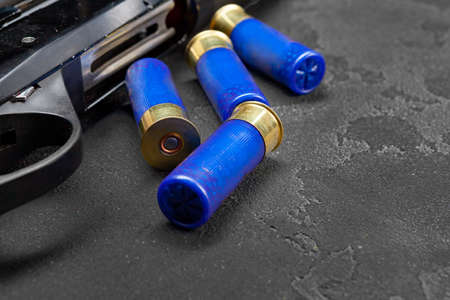 Close up of hunting shotgun and cartridges on dark grey background