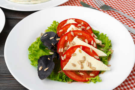 Salad with fresh tomatoes and brined cheese, sunflower seeds on topの写真素材