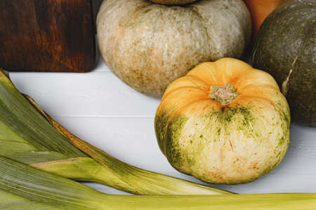 Fresh pumpkin and leek on white table