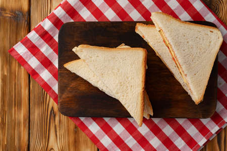 Sandwiches cut into halves on wooden cutting board with napkinの写真素材