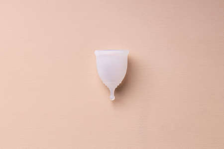 One menstrual cup on beige background top view