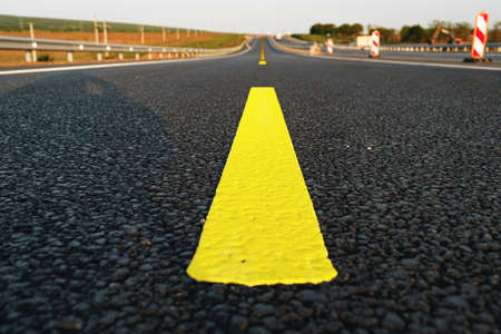 Yellow road markings on asphalt road close up