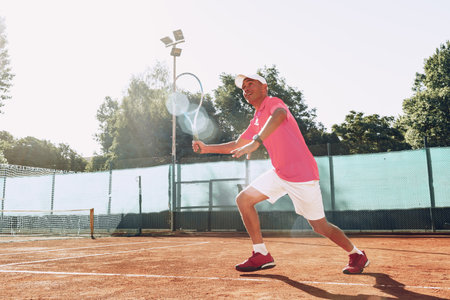 Middle-aged man playing tennis on outdoor tennis filed