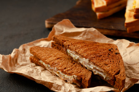 Toasted rye sandwich with ham cut into halves on tableの写真素材