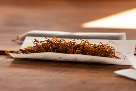 Cigarette paper and pile of tobacco on wooden tableの写真素材