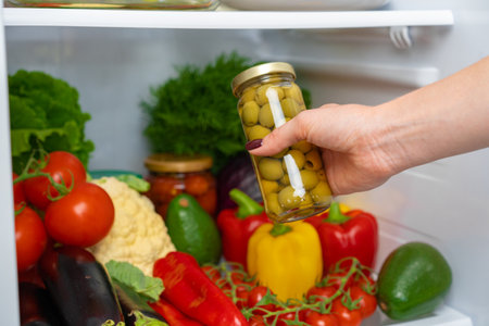 Female hand taking jar of olives from a fridgeの写真素材