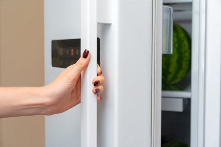 Female hand opens door of a fridgeの写真素材