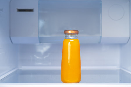 Glass bottle of juice on a fridge shelf