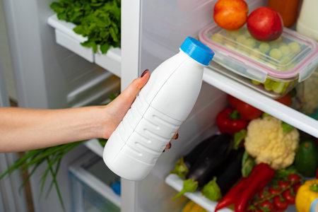 Female hand taking bottle of milk from a fridgeの写真素材