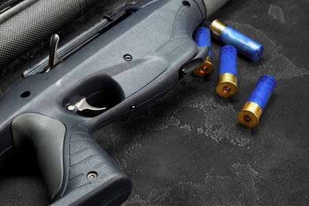 Close up of hunting shotgun and cartridges on dark grey background