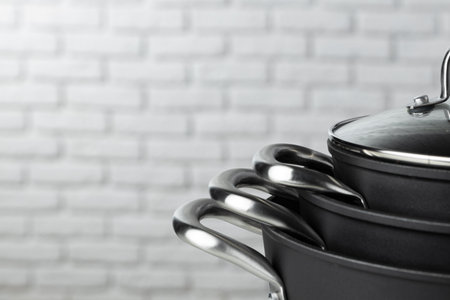Black kitchenware on table against white brick wallの写真素材