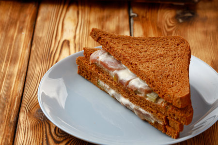 Toasted rye sandwich in plate on wooden tableの写真素材