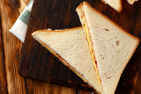 Sandwiches cut into halves on wooden cutting board with napkin