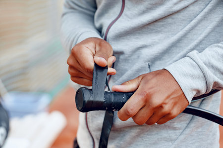 Unrecognizable tennis player repairs coverage of handle of tennis racketの写真素材