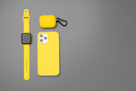 Yellow smartphone, smartwatch and earphones on gray backgroundの写真素材