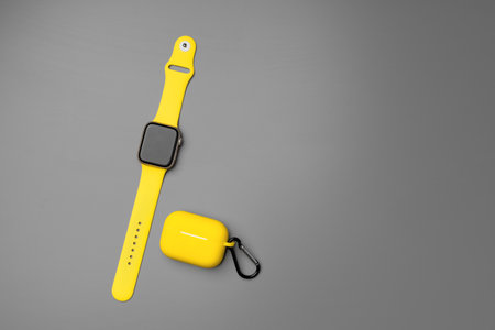 Yellow smartwatch and earphones in case on gray backgroundの写真素材