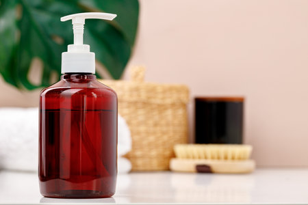 Brown transparent skincare product bottle with dispenser on a light backgroundの写真素材