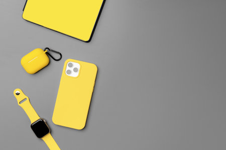 Yellow notepad with smartphone, smartwatch and earphones on gray backgroundの写真素材
