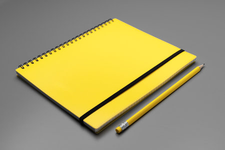 Yellow notepad with yellow pencil on gray backgroundの写真素材