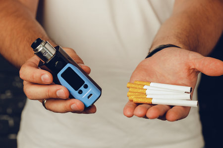 Male holding cigarettes and vape inhaler close up