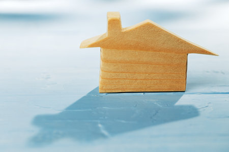 Wooden house miniature on blue background close up