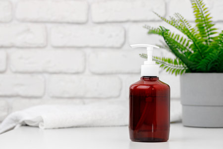 Brown transparent skincare product bottle with dispenser on a light backgroundの写真素材