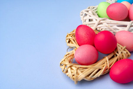 Colorful Easter eggs in decorative nest on blue background