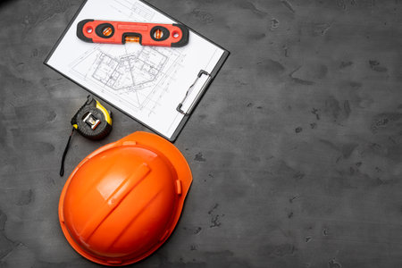 Construction worker hardhat, blueprints and .construction level, top view