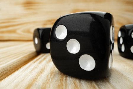 Macro of black tossed dice on wooden backgroundの写真素材