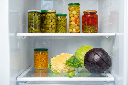 Glass jars of canned products on a fridge shelfの写真素材