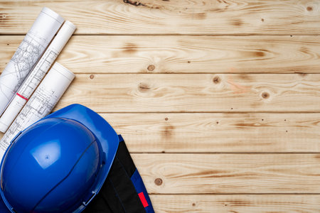 Construction worker unifrom, hardhat and blueprints on wooden backgroundの写真素材