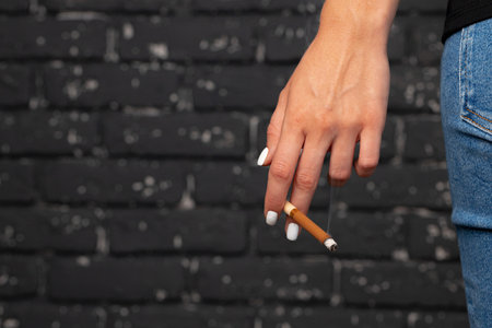 Female hand holding lighted cigarette close upの写真素材