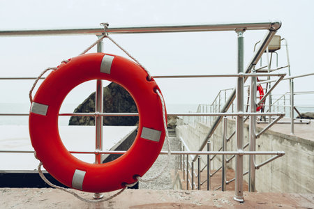 Red lifebuoy hanging on metal .fencing near sea sideの写真素材