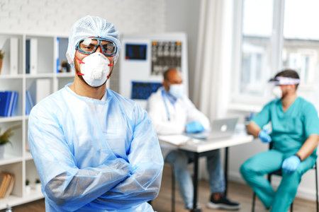 Male doctor in protective medical gown standing in hospital cabinetの写真素材