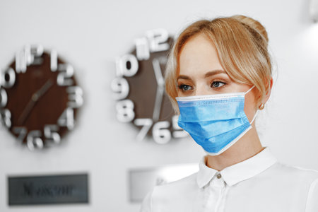 Close up portrait of woman hotel receptionist wearing medical maskの写真素材