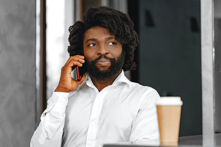 Afro businessman in white shirt talking on the phone