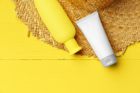 Cosmetic containers and straw hat on yellow backgroundの写真素材