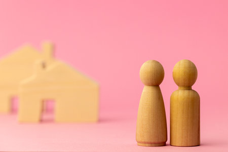 Wooden house miniature and toy people on pink backgroundの写真素材
