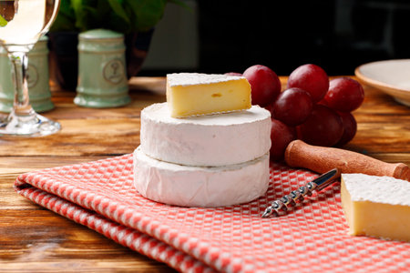 Round white cheese with grapes on wooden tableの写真素材