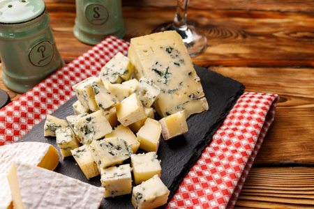 Stone board with cut cheese on wooden table