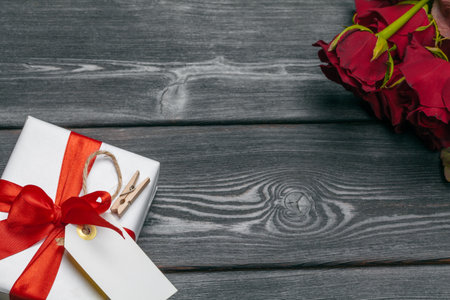 A bouquet of red roses, gift and hearts on table. Concept Womens Day or St. Valentine. Copy spaceの写真素材