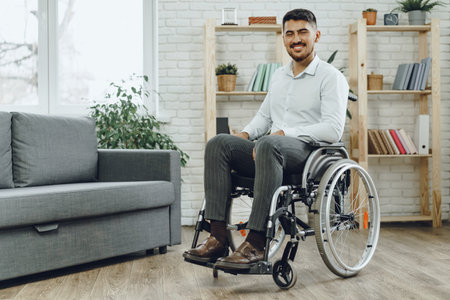 Happy smiling young man in a wheelchair at homeの写真素材