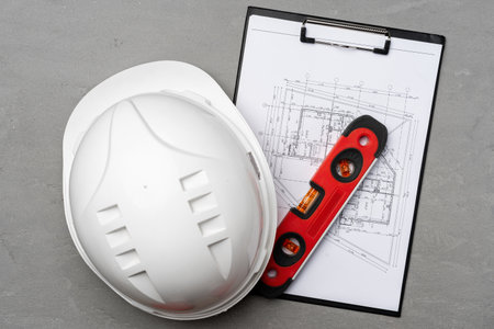 Construction worker hardhat, blueprints and .construction level, top view