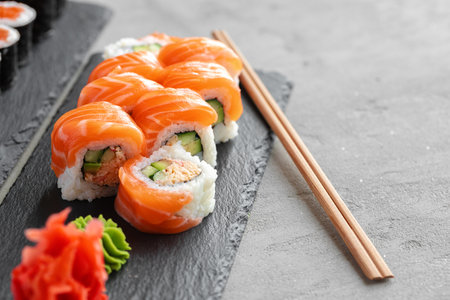 Sushi roll covered with fresh salmon served on plateの写真素材