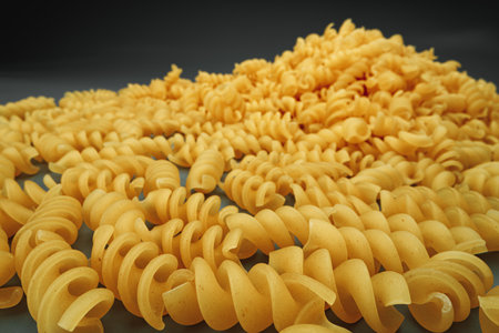 Uncooked pasta swirls on dark background macroの写真素材